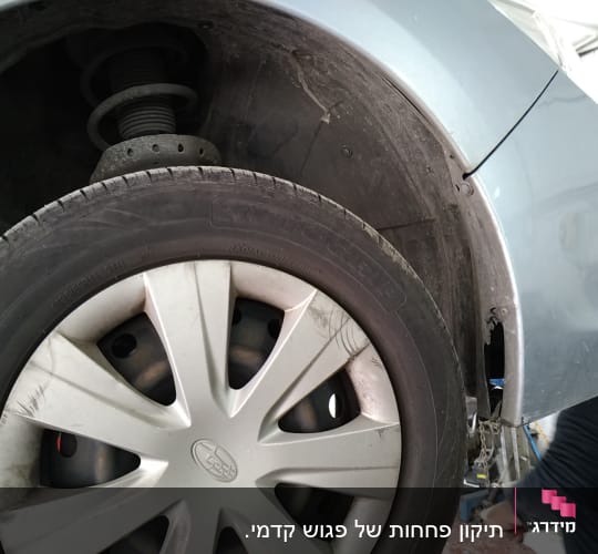 גלגל רכב עם פגוש פגום במוסך